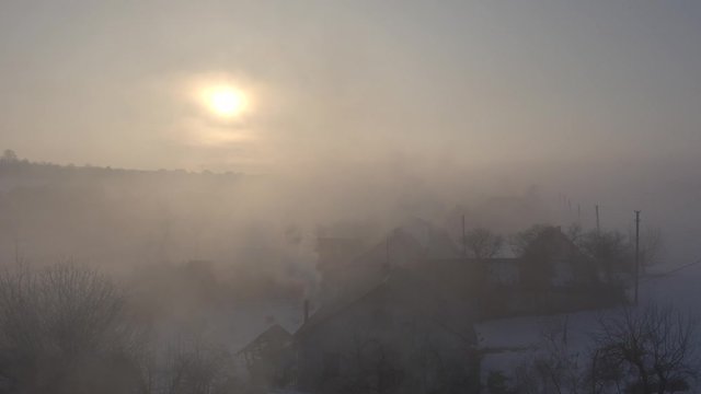 Drone sliding above houses roofs at foggy countryside.