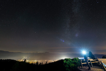 Blick von der Neureuth-Hütte auf den Sternenhimmel über dem nächtlich beleuchteten Rottach-Egern...
