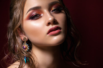 Fototapeta premium Attractive young model with colorful trendy smoky eyes, bright blue eyes, wet hairdo and fashion earring
