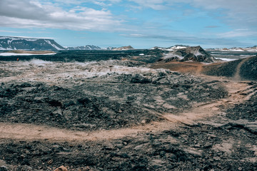 Leirhnjukur old black lava field with a tourist trail and blue sky in Iceland, overcast day in summer , film effect with grain