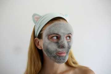 Bubbling mask with charcoal oxygen purifying product on the face of beautiful woman. Skin care mask. Funny headband with ears