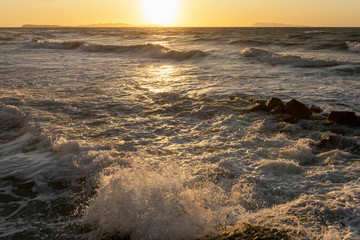 Beauty of the sea -  splashing waves lighted by the sunset. Golden hour hues in semi wild unspoiled Logas Beach, Sidari, Corfu, Greece, Europa.