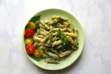 Pasta penne with pesto fresh homemade sauce and cherry and basil. 