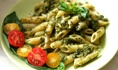Pasta penne with pesto fresh homemade sauce and cherry and basil. 