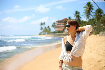 Happy woman traveller enjoying vacation on the beautiful tropical beach in paradise island in Sri Lanka. Freedom concept.