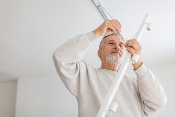 Senior man installing a ceiling light n a freshly renovated appartment