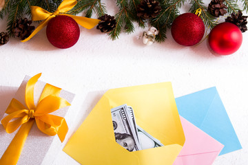 money in an envelope, gift box with a golden bow and Christmas ornaments on a white background,...