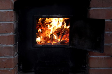 firewood burns in a bright flame in an iron stove