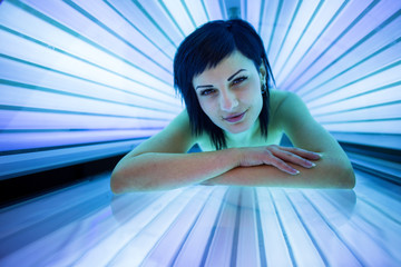 Pretty, young woman tanning her skin in a modern solarium/sunbed