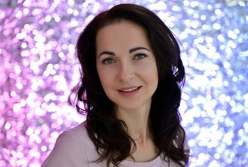 Close-up portrait of an adult pretty brunette woman against the background of bright lights in a studio. Beauty, Art, model posing.
