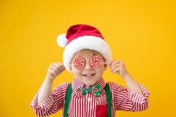 Happy child holding lollipop in hand against yellow background