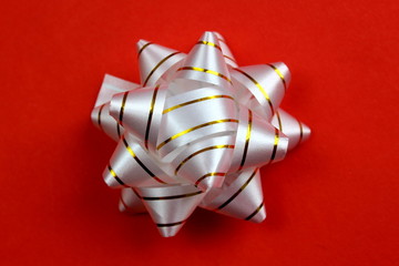 packing bow of white color with golden stripes on a red background
