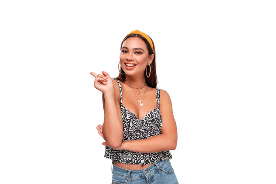 Pretty african-american teenager in a headband, sleeveless t-shirt and jeans wagging a finger standing isolated over white background. Place for advertisement. Concept of rebuke.