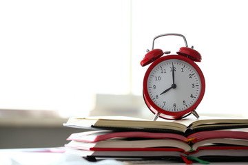 Red alarm clock set at eight in the morning closeup standing on pile of books. Business or education concept