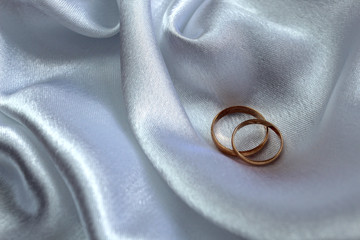 gold wedding rings lie on satin fabric