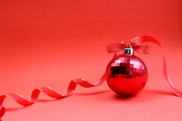 red toy ball for the Christmas tree with a red ribbon on a red background