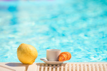 Delicious breakfast lemon, coffee, croissant by the pool