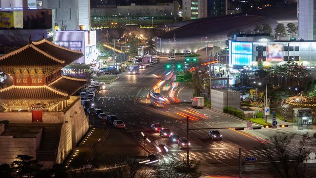 Timelapse famous Heunginjimun and Dongdaemun Design Plaza buildings near multi-lane road with heavy traffic and bright illumination in Seoul at night zoom in