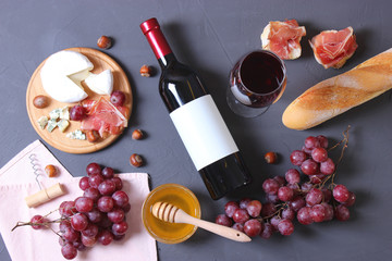 red wine and snacks on the table top view. Wine, prosciutto, cheese, baguette, grapes, honey.