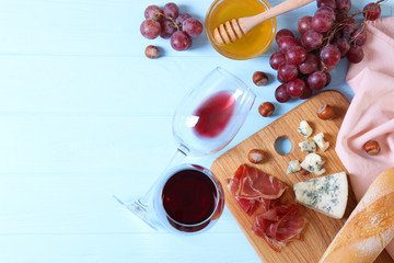 red wine and snacks on the table top view. Wine, prosciutto, cheese, baguette, grapes, honey.