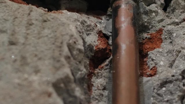 Damaged water pipe in the bathroom wall; missing isolation on the copper pipe; close up shot; camera tilting down