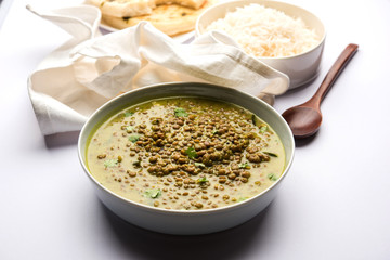 Black Masoor Dal fry or Dhaba Style Sabut Red Lentil dhal tadka in green curry, served in a bowl. selective focus