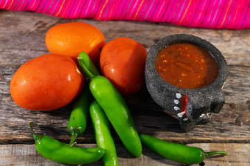 Mexican red sauce in molcajete bowl and raw ingredients
