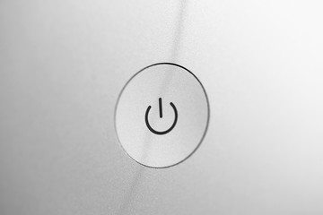 Silver coarse turn on and off button at gray blank back panel of electronic gadget closeup