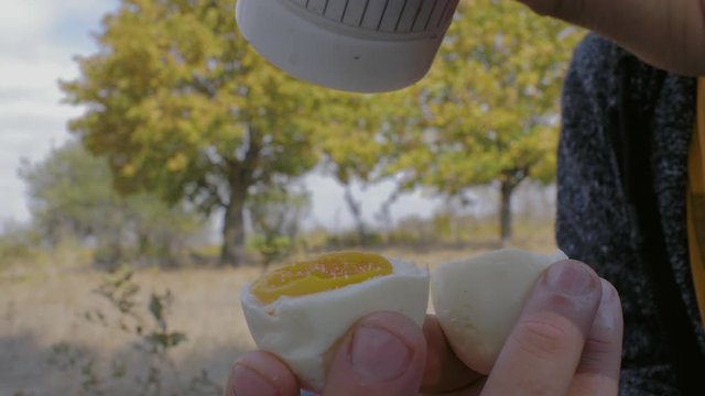 man salt boiled egg holding in his hand on a background of autumn trees. close-up boiled eggs in a male hand. 4k. 4k video. slow motion. 23.98 fps