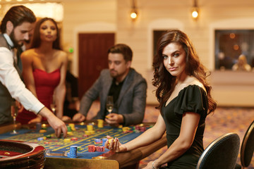 A young woman sitting at table roulette playing poker at a casino.