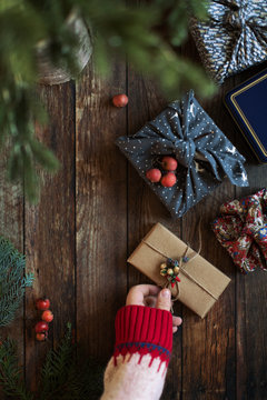 Hand fixing tiny old porcelain berries to a gift wrapped in kraft paper