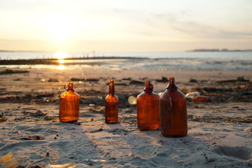 Sunset rays passing through old brown glass bottles on the beach
