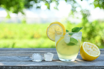 Glasses of lemon juice on a wooden table, summer set, outdoor greed blured background,boke.Water...