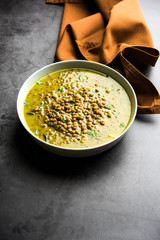 Black Masoor Dal fry or Dhaba Style Sabut Red Lentil dhal tadka in green curry, served in a bowl. selective focus