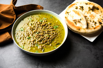 Black Masoor Dal fry or Dhaba Style Sabut Red Lentil dhal tadka in green curry, served in a bowl. selective focus