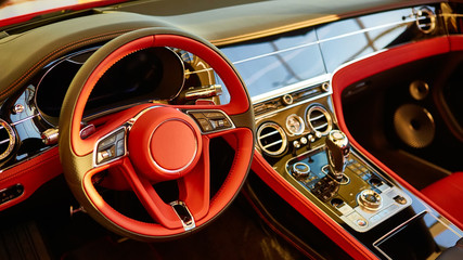 Red luxury car Interior. Steering wheel, shift lever and dashboard. Shallow doff