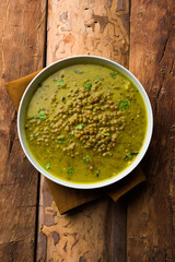 Black Masoor Dal fry or Dhaba Style Sabut Red Lentil dhal tadka in green curry, served in a bowl. selective focus