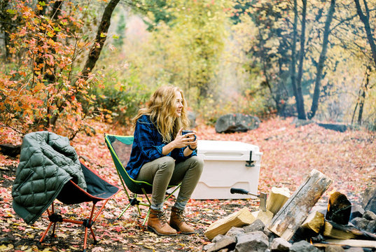 Girl drinking coffee next to camp fire