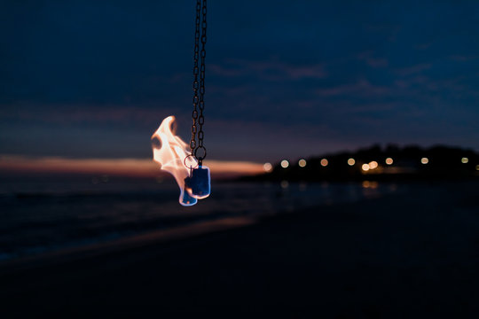 Detail of woman with fire pois on the beach at sunset