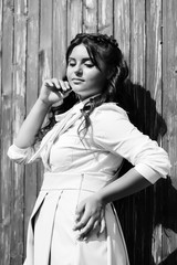Obraz premium Teen girl wearing student uniform, her smiling happy on a wooden wall background. Young girl, autumn mood. Pretty girl with hair style and make up. Fashion, beauty, health. Black and white