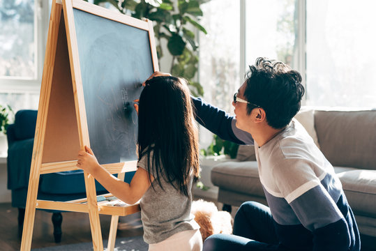 Father and daughter drawing on blackboard at home
