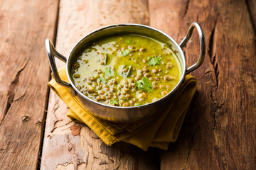 Black Masoor Dal fry or Dhaba Style Sabut Red Lentil dhal tadka in green curry, served in a bowl. selective focus