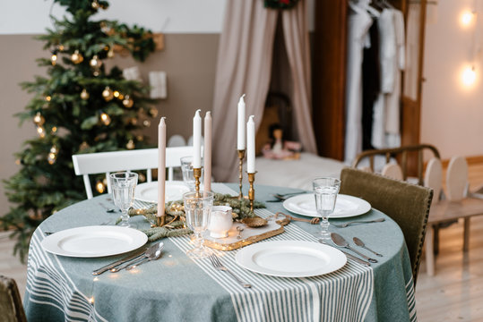 Table served by plates, cutlery and candles near fir tree - Powered by Adobe