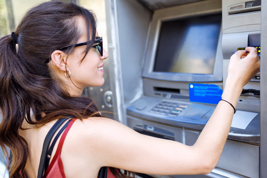 Casual woman using ATM machine
