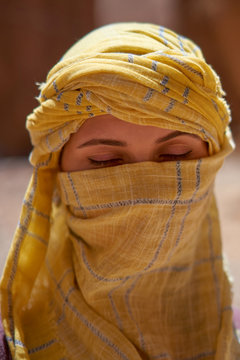 Portrait of the woman with closed eyes and tied yellow berber tagelmust scarf. 