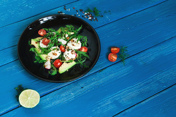 salad of arugula, avocado, cottage cheese, radish and cherry tomatoes on a black glossy plate