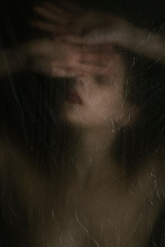Sensual woman in dark behind plastic