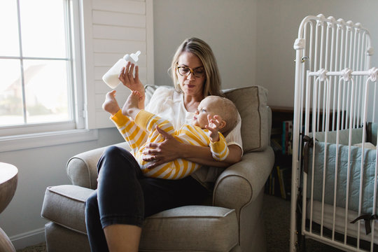 mother trying to bottle feed her distracted baby