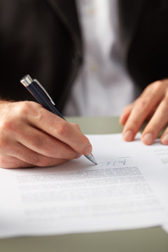 Closeup of man signing paper