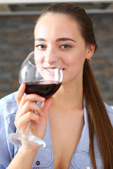 Young beautiful attractive girl drinks wine in the kitchen from a glass at breakfast time, spends her day off with alcohol write a message to a former boyfriend and smiles ex